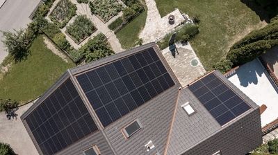 Draufsicht aus der Vogelperspektive auf ein Haus mit Garten und montierter PV-Anlage.