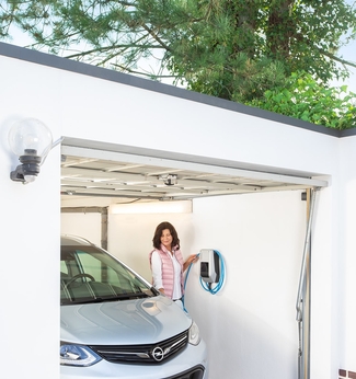 Eine Frau lädt ihr Elektroauto mit einer Wallbox in ihrer Garage auf.