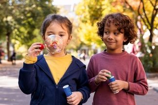Kinder spielen im Park und blasen Seifenblasen