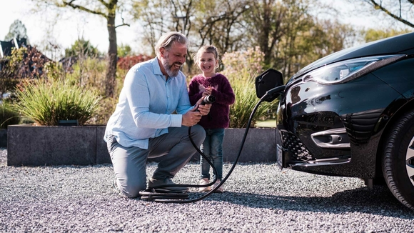 Vater und Tochter laden Elektroauto auf