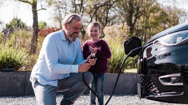 Vater und Tochter laden Elektroauto auf
