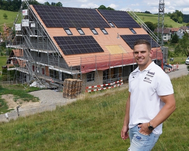 Der Schwinger Remo Käser steht vor seinem Haus auf dem gerade eine Solaranlage montiert wird.